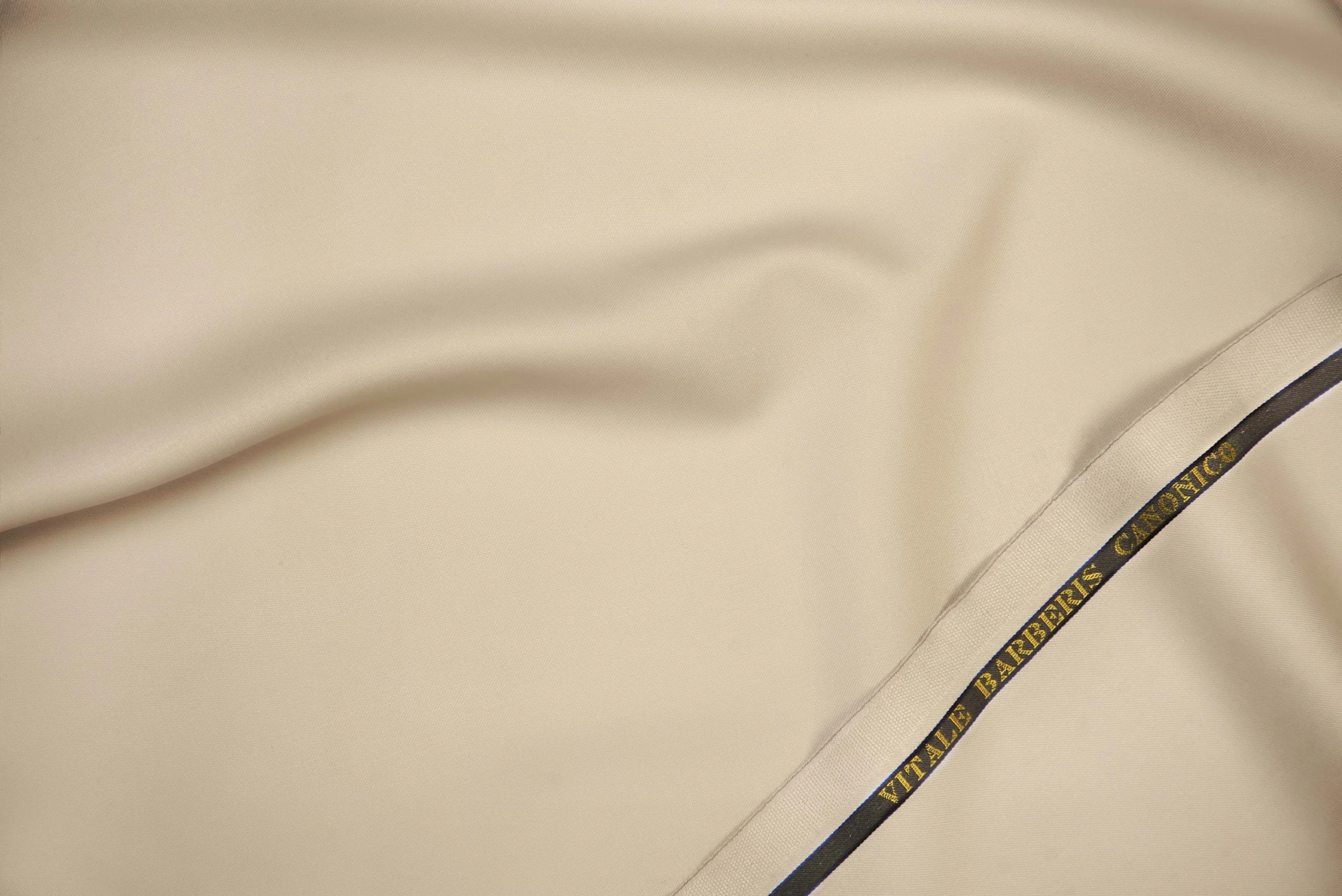 VBC beige plain weave wool suiting fabric close-up, smooth ceremonial wool with structured drape, luxury Italian fabric for formal suits, daytime weddings, and bespoke tailoring in warm neutral tones