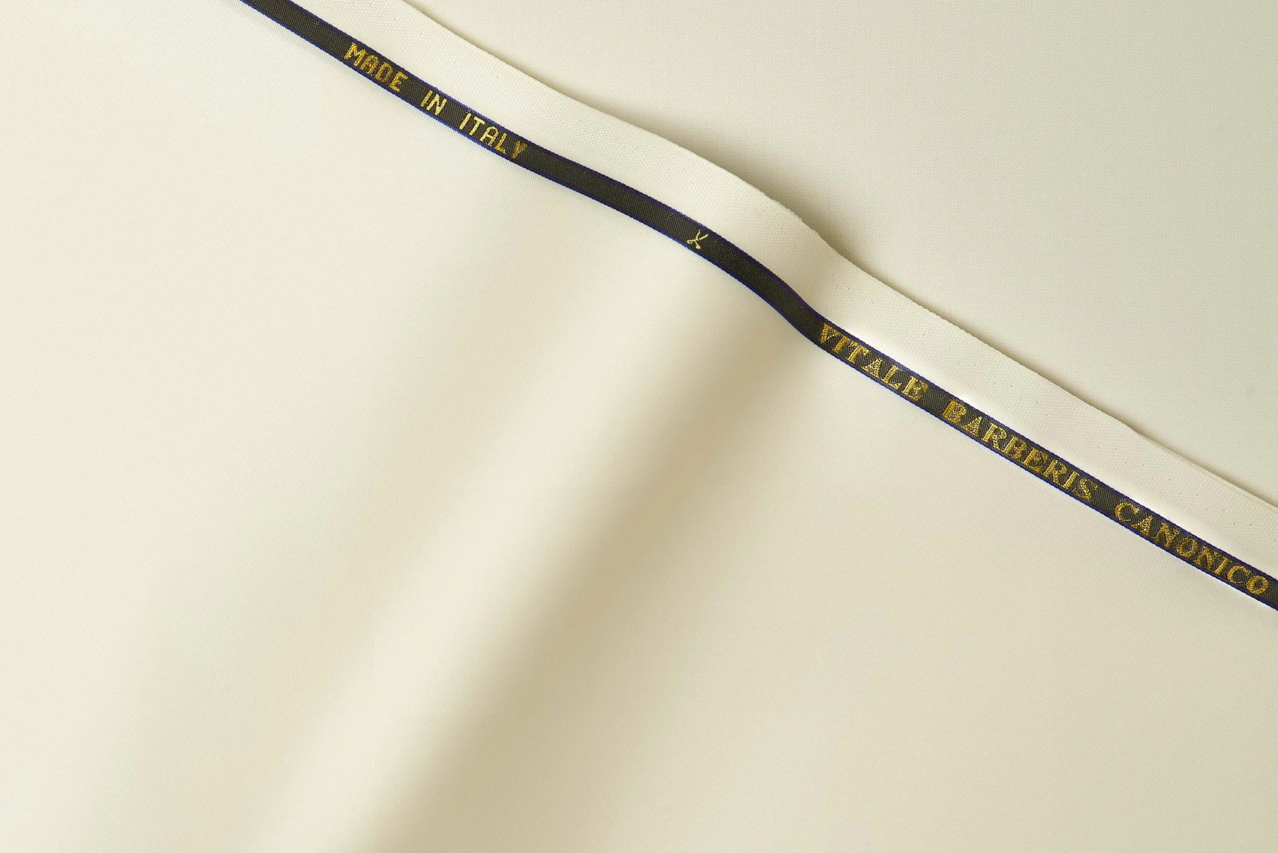 VBC cream plain weave wool suiting fabric close-up, smooth ceremonial wool with structured drape, luxury Italian fabric for formal suits, daytime weddings, and bespoke tailoring in warm neutral tones