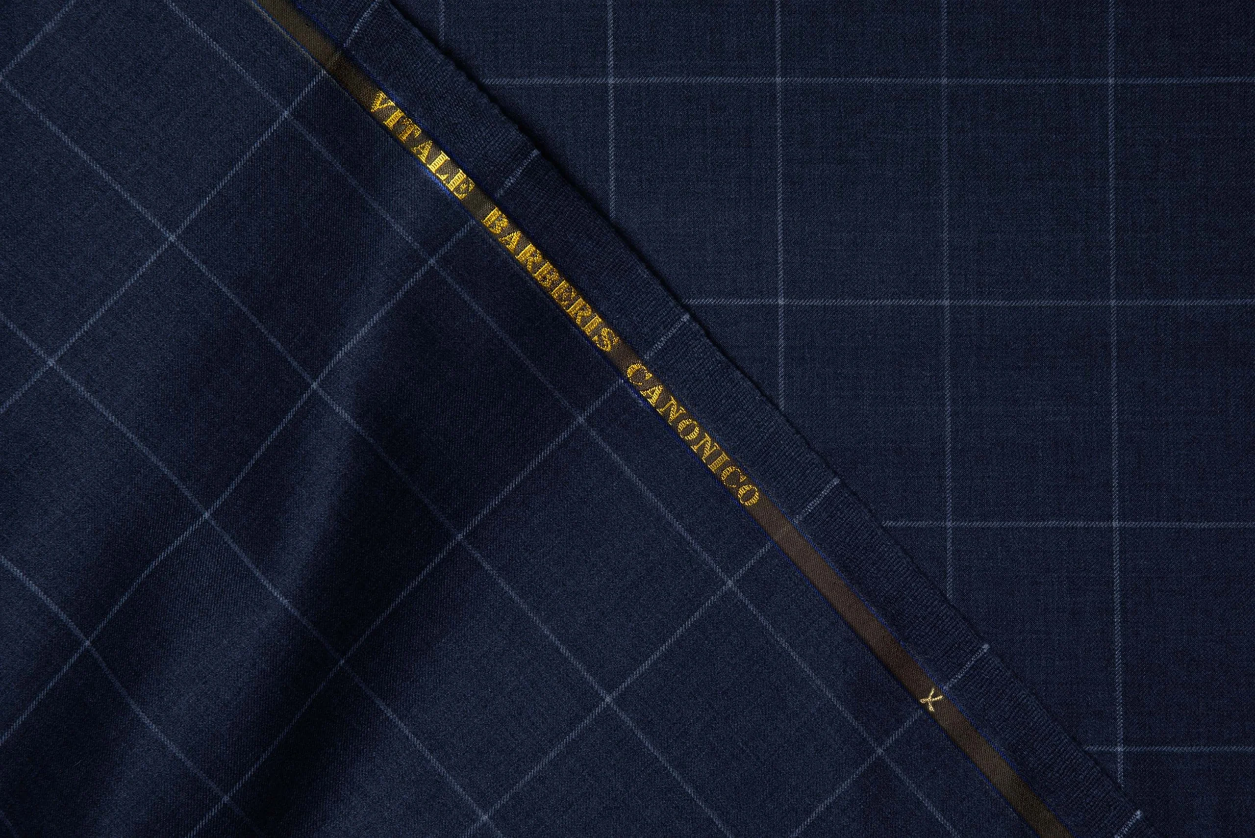 VBC dark blue windowpane check wool suiting fabric close-up, fine Italian wool with structured drape and subtle grid pattern, luxury fabric for business suits, formal tailoring, and bespoke menswear craftsmanship