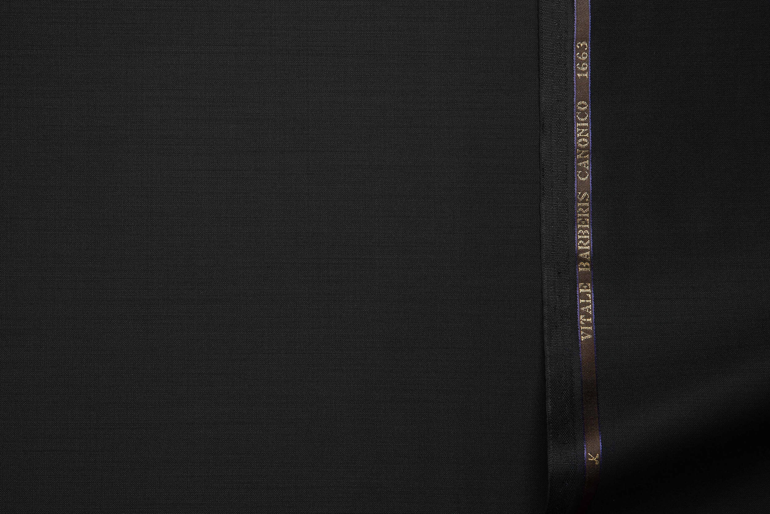 VBC black plain weave wool suiting fabric close-up, smooth dense surface with structured drape, luxury Italian ceremonial fabric for tuxedos, formal suits, evening wear, and bespoke tailoring craftsmanship
